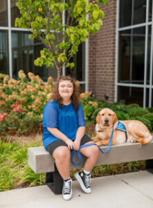 Chelsea and her service dog, Hector. He is a yellow lab.